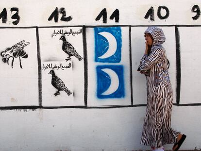 Una marroquí pasa delante de un cartel con los símbolos electorales de los partidos en Rabat.