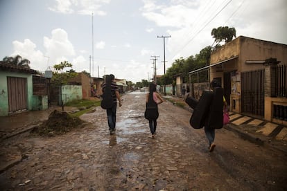 Tres jóvenes integrantes de la orquesta de Cateura vuelven a casa con sus instrumentos tras asitir a la escuela de música en la barriada de Asunción (Paraguay) el 21 de diciembre de 2013 durante una inundación. 