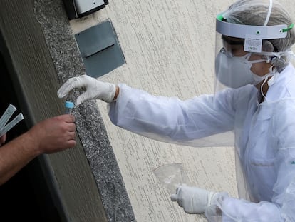 Homem recebe na terça, 14 de abril, um teste de coronavírus de um profissional da saúde na porta de sua casa, em São Caetano do Sul, São Paulo.