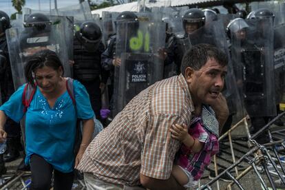 Un hombre protege a su bebé después de que la Policía mexicana lanzara gases para contener a los migrantes en el puente Rodolfo Robles.