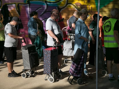 Varias personas esperan para el reparto de alimentos en un barrio de Madrid.