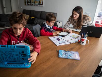 Mujer teletrabajando en casa mientras ayuda a sus hijos con los deberes, en Madrid.