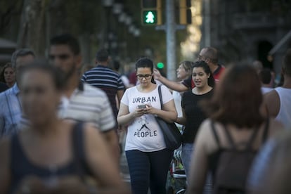 Una peatón mira el móvil mientras cruza un paso de cebra.