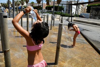 Dos niñas se refrescan en una plaza céntrica de Almería.