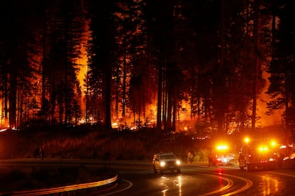 Un vehículo pasa mientras los bomberos permanecen junto a la carretera cerca de un incendio,en Jonesville, California.