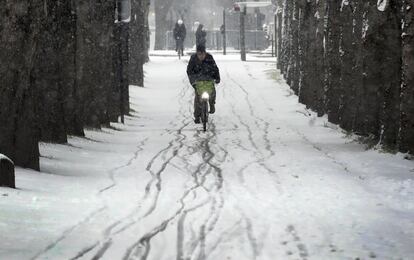 Un hombre conduce una bicicleta en una calle nevada de París.