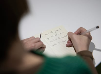 Una mujer escribe en una libreta la palabra solo sin tilde.