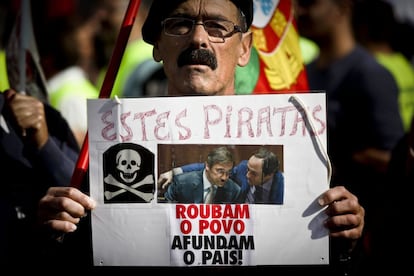 Un manifestante muestra una pancarta con el lema &quot;Estos piratas roban al pueblo, hunden el pa&iacute;s&quot; con las fotos del primer ministro portugu&eacute;s, Pedro Passos Coehlo (izq), y del viceprimer ministro, Paulo Portas.