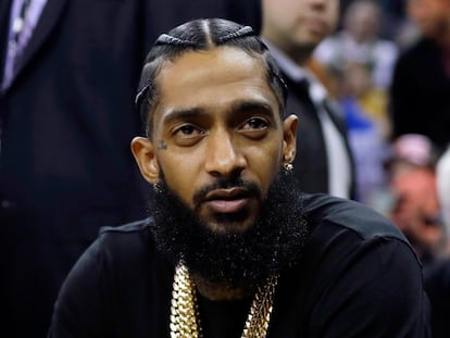 Rapper Nipsey Hussle attends an NBA basketball game between the Golden State Warriors and the Milwaukee Bucks in Oakland, Calif., March 29, 2018.