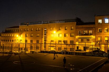 Dos niños juegan a la pelota a oscuras en una pista de fútbol en Vallecas.
