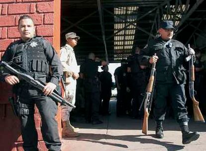 Un oficial de la policía local sale, cargado con dos fusiles, del cuartel general de Tijuana, vigilado por el Ejército y la policía federal.