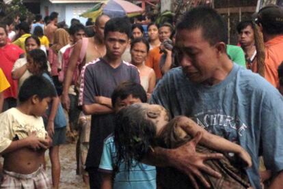 Un hombre llora mientras lleva en brazos a su hija muerta en Cagayán de Oro.