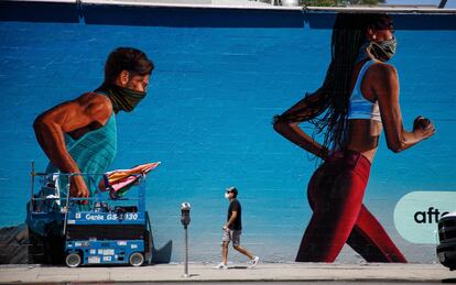 Un joven pasa delante de un mural de una calle de Hollywood (California).