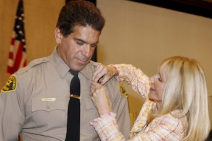 Ferrigno se coloca la estrella de ayudante del <i>sheriff</i> con ayuda de su mujer, Carla.