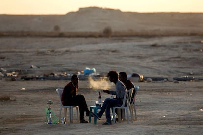 Unos refugiados eritreos fuman de pipas de agua y beben en el exterior del centro de detenci&oacute;n de Holot, en el desierto de Negev, cerca de la frontera entre Israel y Egipto.