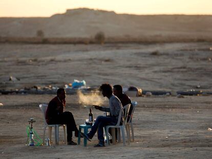 Unos refugiados eritreos fuman de pipas de agua y beben en el exterior del centro de detenci&oacute;n de Holot, en el desierto de Negev, cerca de la frontera entre Israel y Egipto.