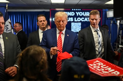 Former president and Republican presidential candidate Donald Trump signs an autograph as he campaigns in Newton, Iowa, on January 6, 2024.