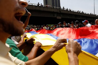 Un grupo de protestantes en contra de Nicolás Maduro sostienen la bandera de Venezuela.