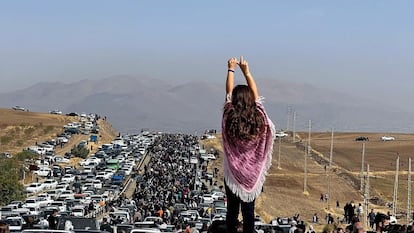 Una joven sin velo alza los brazos ante una multitud que trataba de llegar al cementerio de Aichi, donde está enterrada Mahsa Amini, para rendirle homenaje, el 26 de octubre de 2022.