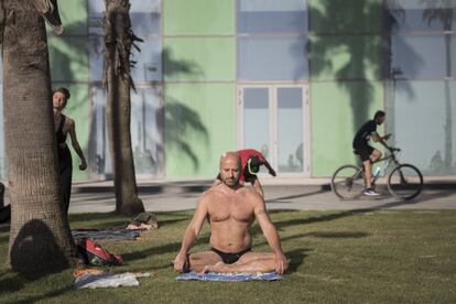 Un hombre hace meditación en la playa de la Barceloneta.