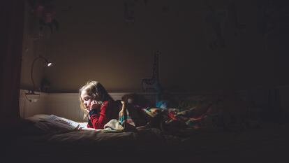 Una niña lee por la noche en su cama.