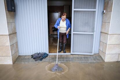 Una mujer saca el agua del interior de su casa con una fregona, este viernes en Valencia.