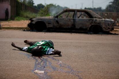 Un hombre yace muerto en medio de una calle al lado de un coche quemado, tras un tiroteo con las fuerzas de paz, en Bangui, República Centroafricana.