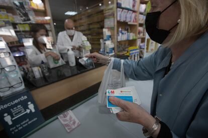 Una mujer compra medicamentos en una farmacia con su tarjeta sanitaria en Madrid, el pasado 2 de junio.