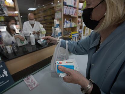 Una mujer compra medicamentos en una farmacia con su tarjeta sanitaria en Madrid, el pasado 2 de junio.