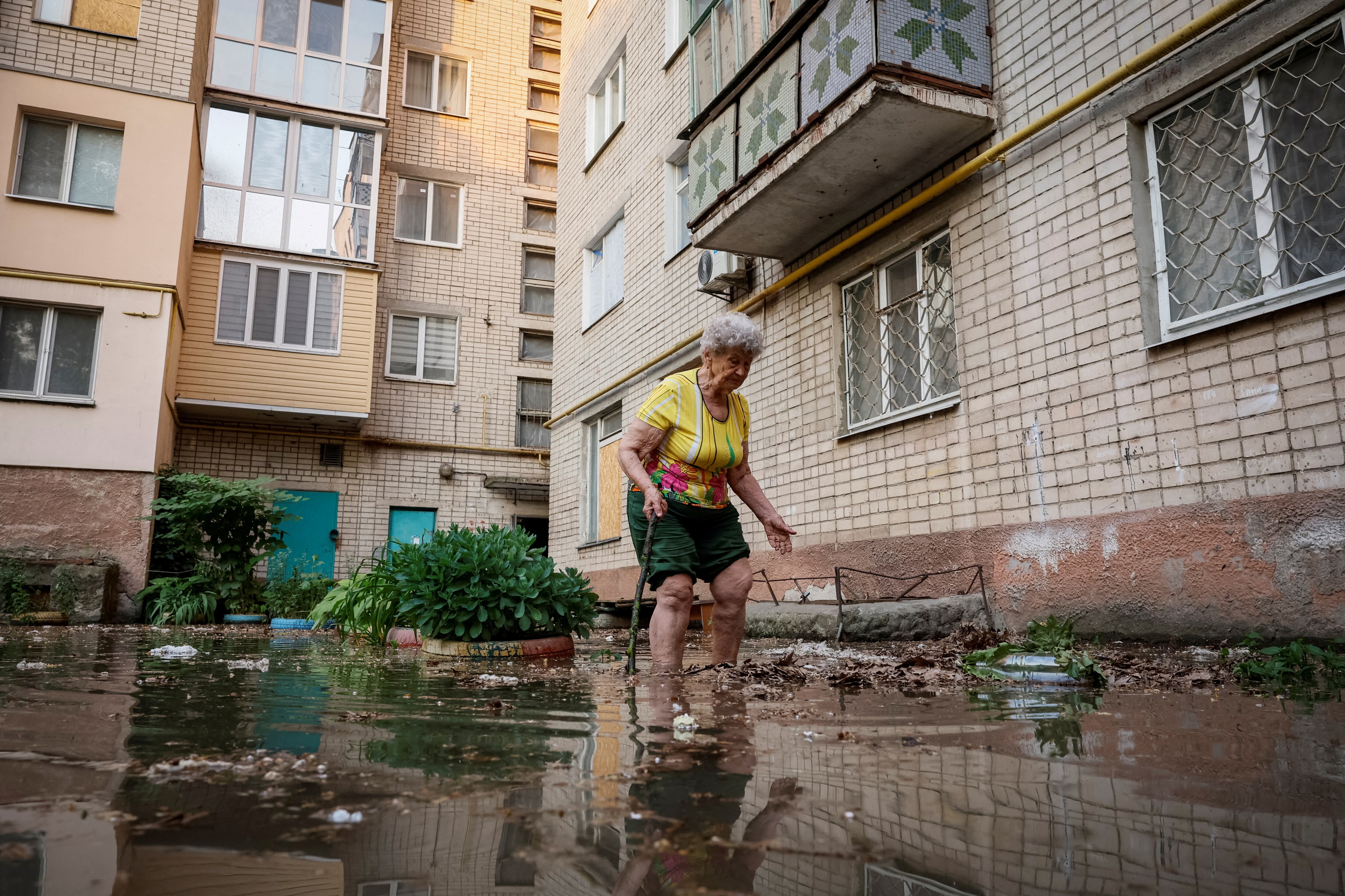 Una mujer camina alrededor de su casa en una calle inundada, después de que se rompiera la presa de Nova Kajovka, el 6 de junio.