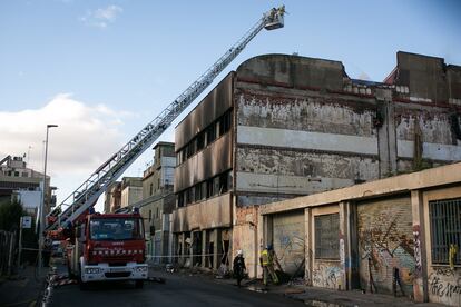 Los bomberos trabajan en el exterior de la nave incediada en Badalona, este jueves.