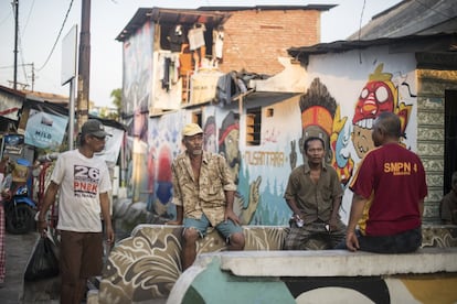 Unos vecinos del kampung Kedondong, un humilde barrio a unos metros del lujoso centro comercial Tunjungan Plaza, en Surabaya, delante de uno de los murales de X-Go y su cuadrilla de artistas.