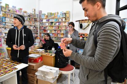 Julián Ramírez (derecha) muestra las figuritas que acaba de comprar en el comercio de Juan Vargas (en segundo plano), en el centro de Buenos Aires, el 14 de septiembre de 2022.