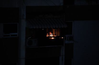 Um homem usa uma vela para iluminar a sala de sua casa em um prédio afetado pelo blecaute elétrico nacional, nesta terça-feira. Durante o último episódio da falha elétrica na Venezuela, houve mais de 300 estabelecimentos saqueados na cidade de Maracaibo, provavelmente a mais afetada pelo desgoverno exposto durante a crise.