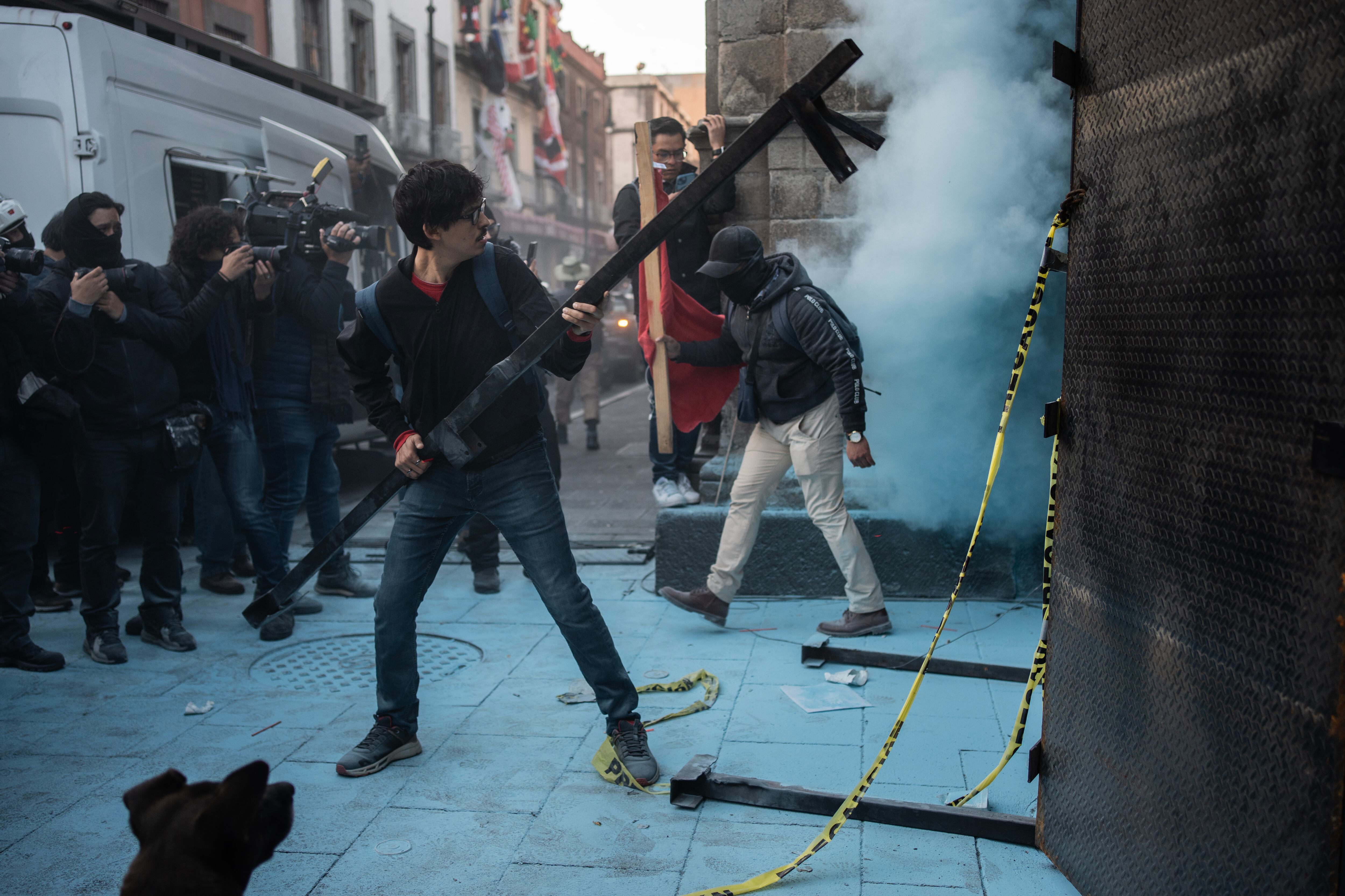Maestros de la CNTE intentan derribar las vallas instaladas en Palacio Nacional, esta mañana.