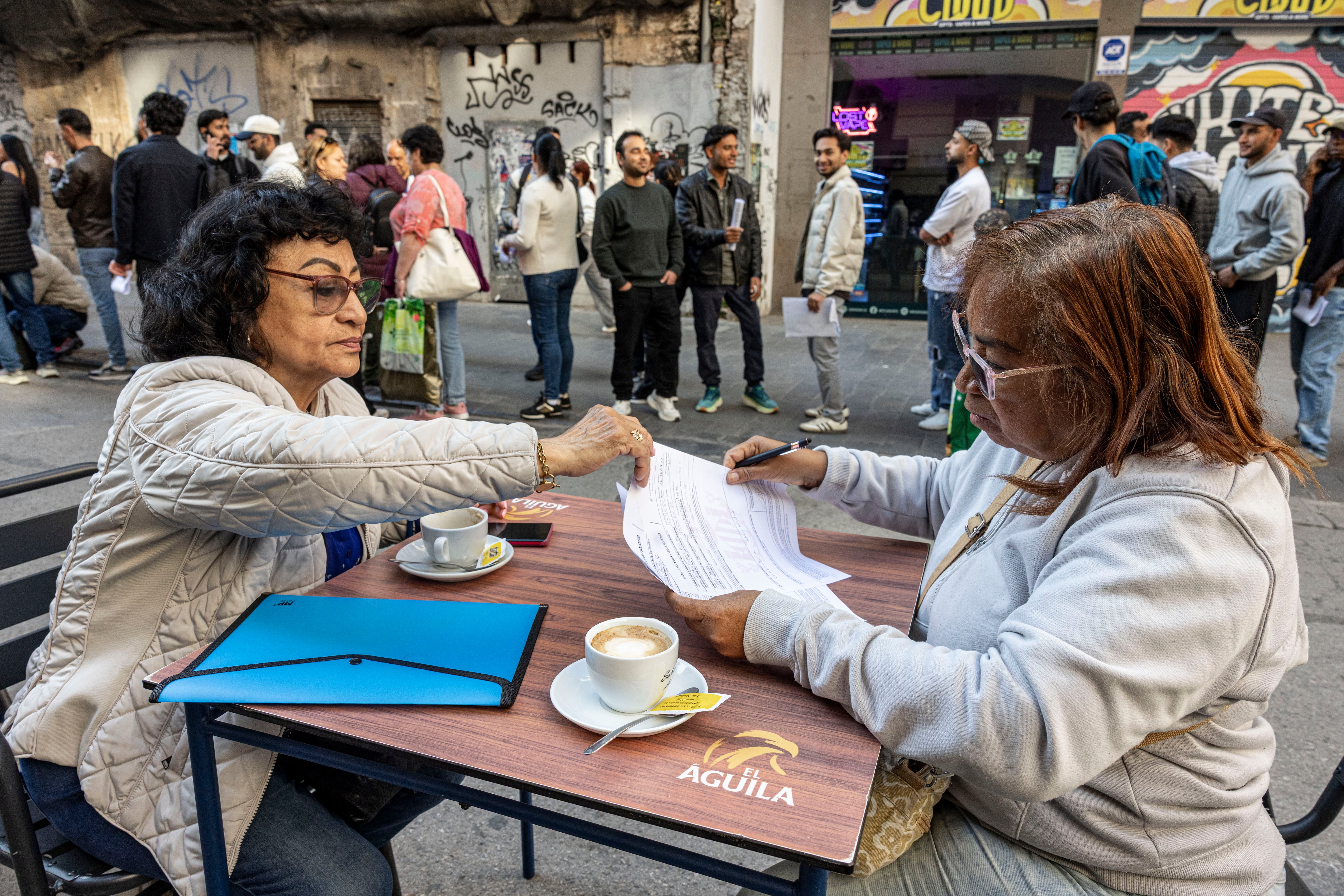 Dos mujeres cumplimentan documentos para regularizar su situación, este lunes en Valencia.