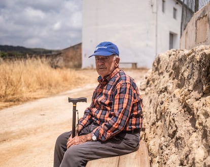 Pepe López, vecino de Casas de Moya, sentado en un banco del pueblo después de haberse marchado durante una noche por la amenaza del fuego.