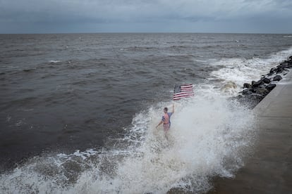 Una persona sostiene una bandera estadounidense y es salpicada por una ola rompiente mientras el huracán Helene se intensifica antes de su esperada llegada a tierra en el Big Bend de Florida, en Alligator Point, Florida.