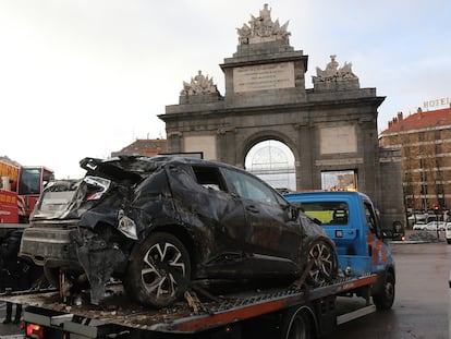 Una grúa transporta un coche siniestrado en la Puerta de Toledo de Madrid.