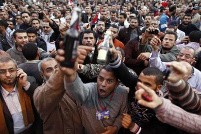 Seguidores de Morsi muestran botellas de bebidas alcohólicas que supuestamente han encontrado en el campamento que los opositores plantaron en la víspera frente al palacio presidencia.