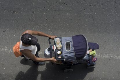 Wilmer Arriaga, um migrante hondurenho, empurra o carrinho de sua sobrinha Loreli pela estrada principal da Guatemala.