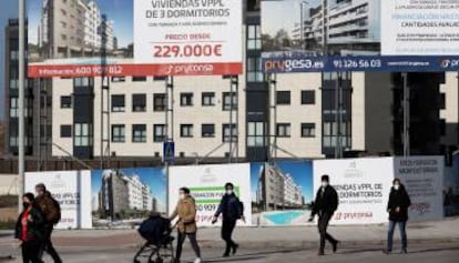 Varios viandantes pasan ante una promoción de viviendas en construcción.