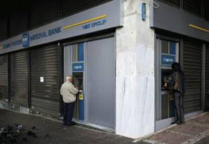 Clientes utilizan cajeros automáticos en una sucursal del Banco Nacional de Grecia, en en centro de Atenas.