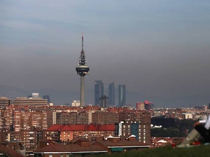 A couple look out at a smog-stained Madrid skyline.