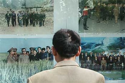 Un chino mira un panel con fotos del <i>gran líder</i> en la puerta de la embajada de Corea del Norte en Pekín.