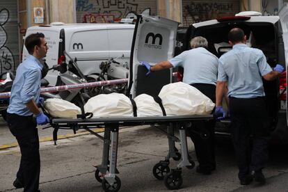 Miembros de los servicios funerarios trasladan uno de los cuerpos.