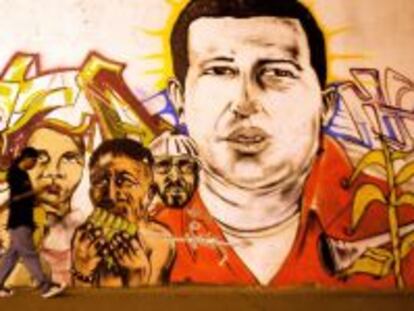 Un hombre pasea por delante de un mural de Hugo Ch&aacute;vez.