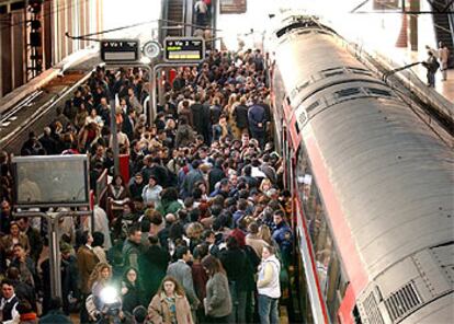 Numerosos viajeros esperan en los andenes de la estación de trenes de Atocha para subirse a los trenes de Cercanías de Renfe.