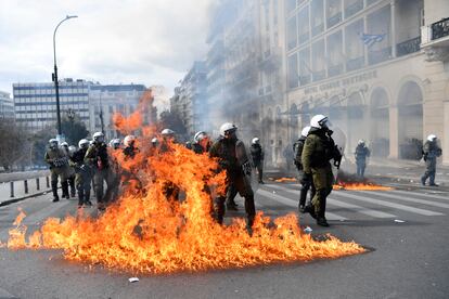 Agentes antidisturbios, entre las llamas de un cóctel molotov, durante la protesta de este jueves en Atenas.  