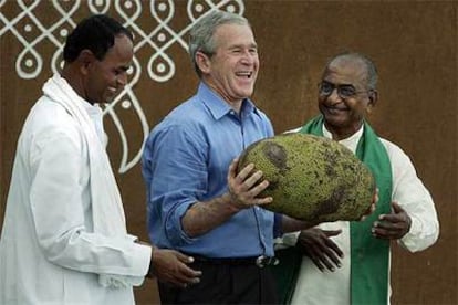 George W. Bush sonríe al exhibir una gran fruta típica de India durante su visita a Hyderabad, en el centro del país.